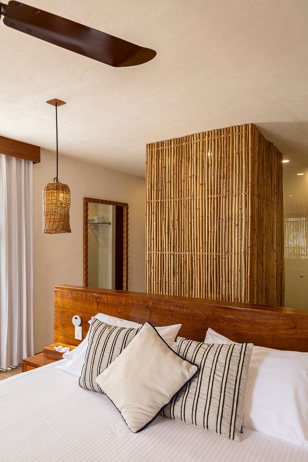 Bedroom with bed, bamboo screen, pendant light, and wooden headboard.
