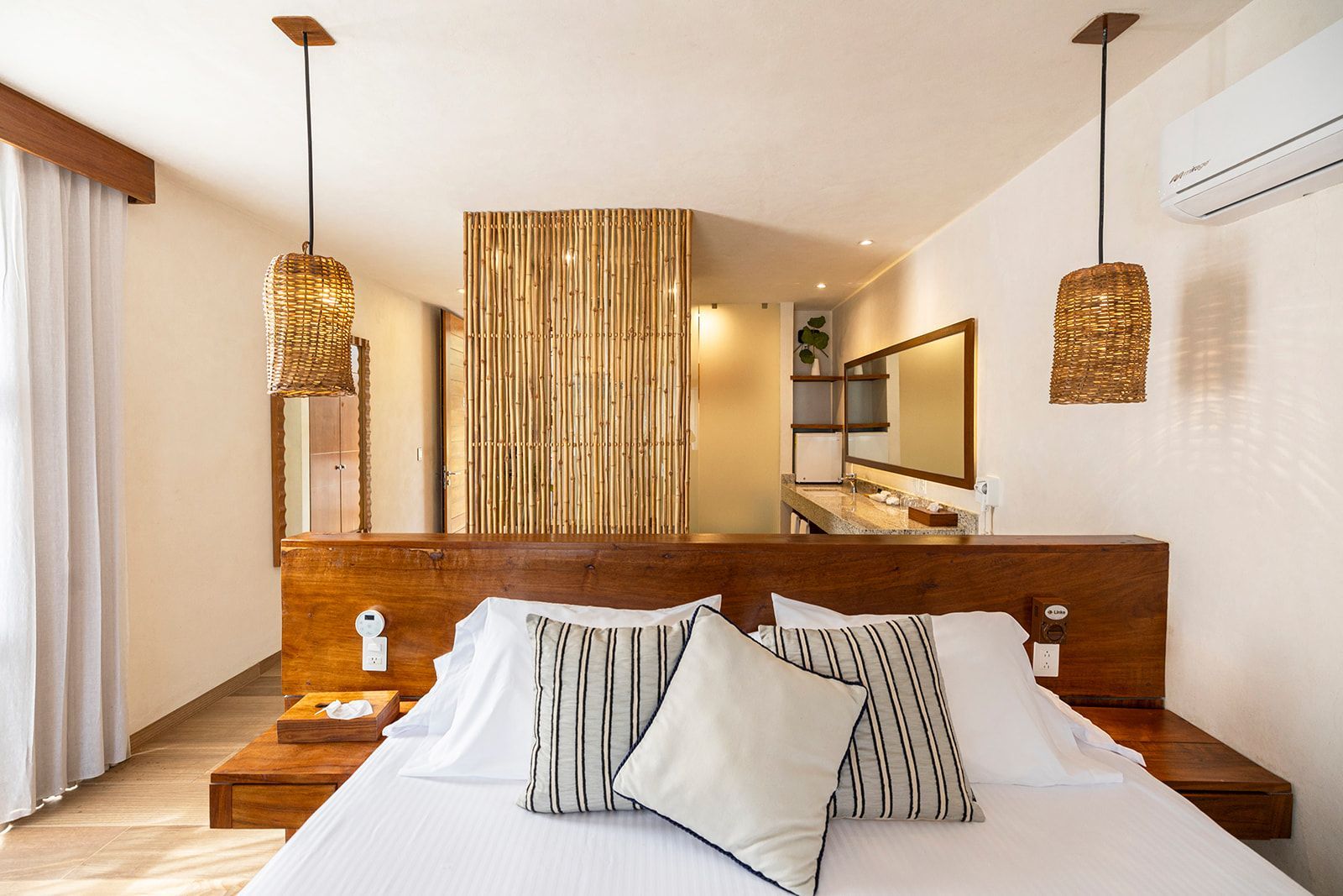 Bedroom with wooden headboard, pendant lights, and bamboo divider.