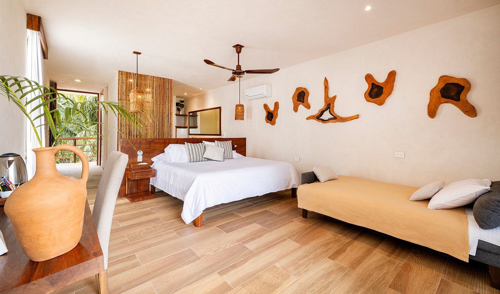 Bedroom with light wood floors, bed with white bedding, wooden wall decor, and a sofa.