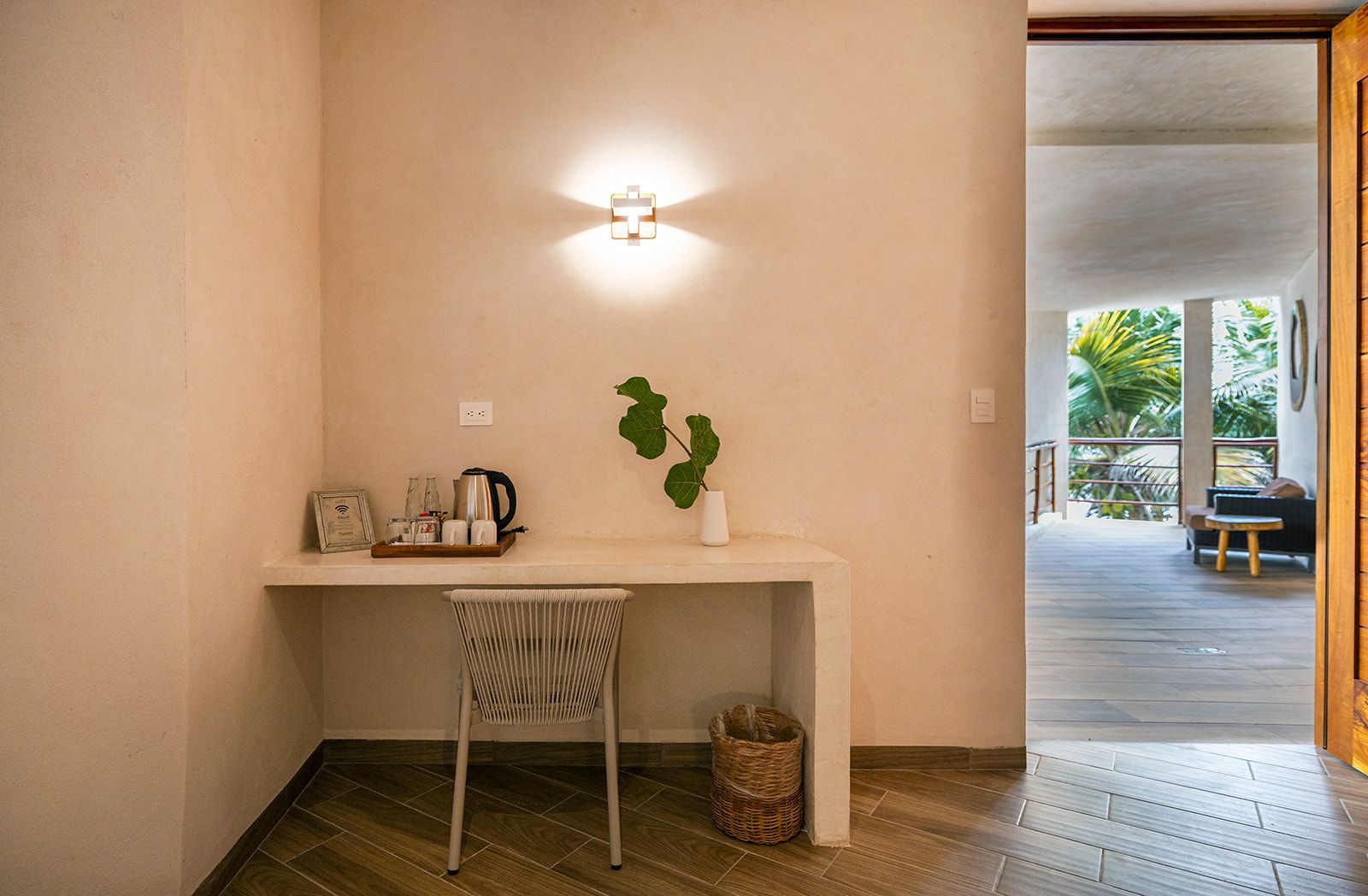 A minimalist desk area with a zebra-print chair, tea set, and greenery, next to an open doorway.
