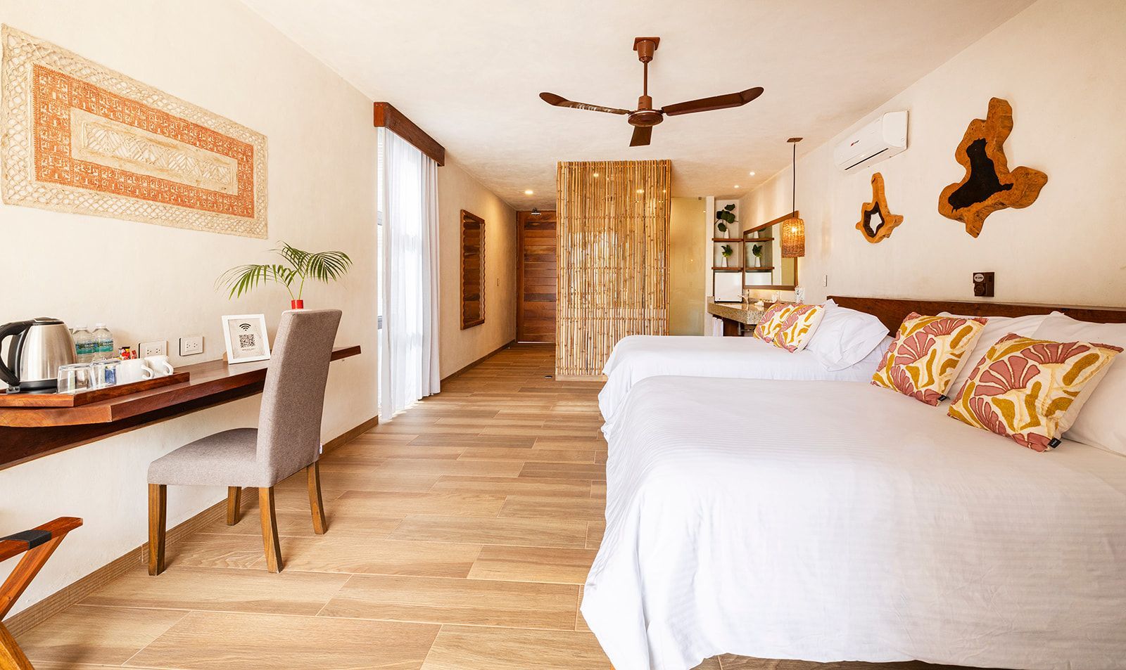 Hotel room with two beds, desk, wooden floors, and decor.