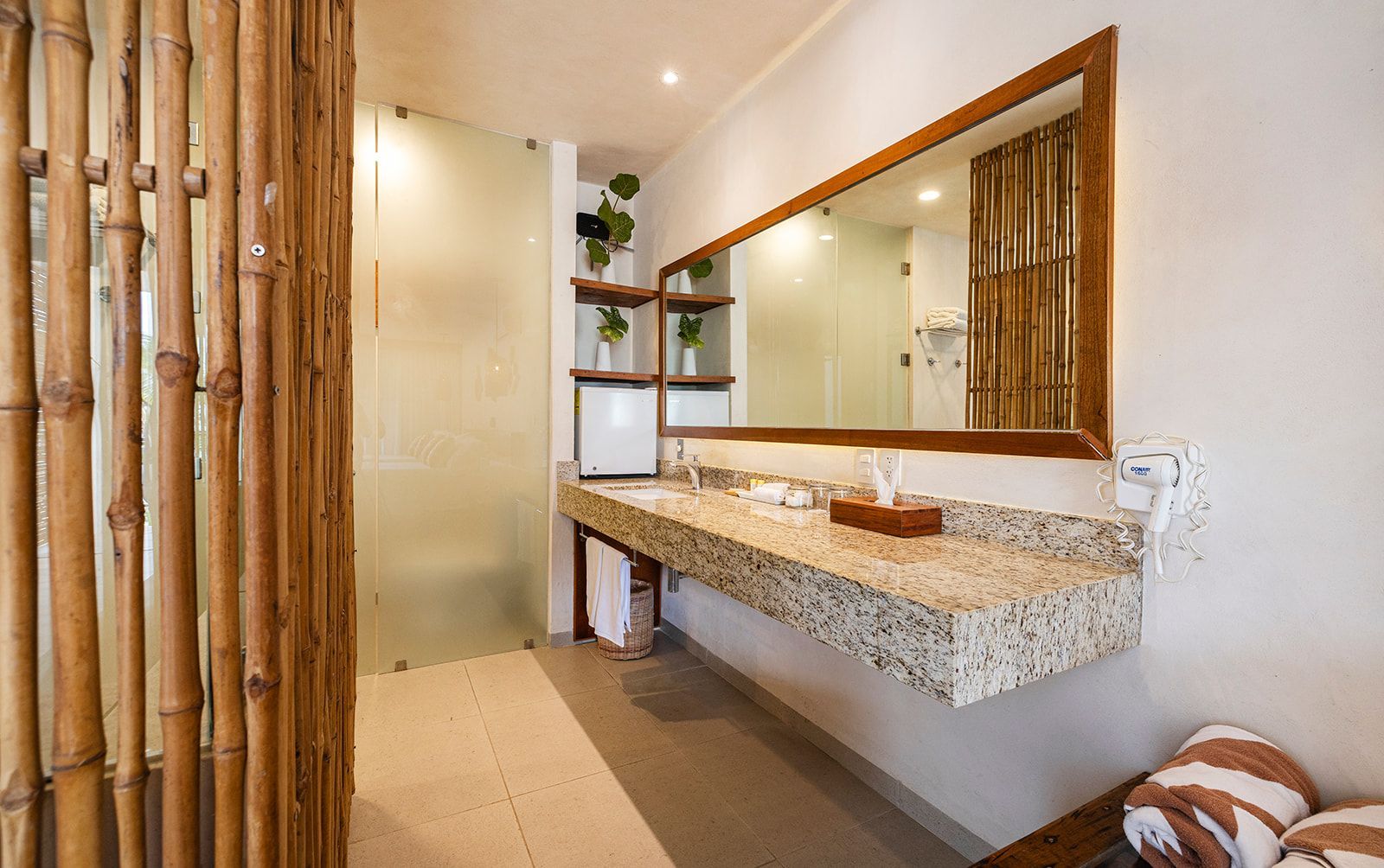 Bathroom with bamboo accents, granite countertop, large mirror, and glass shower door.