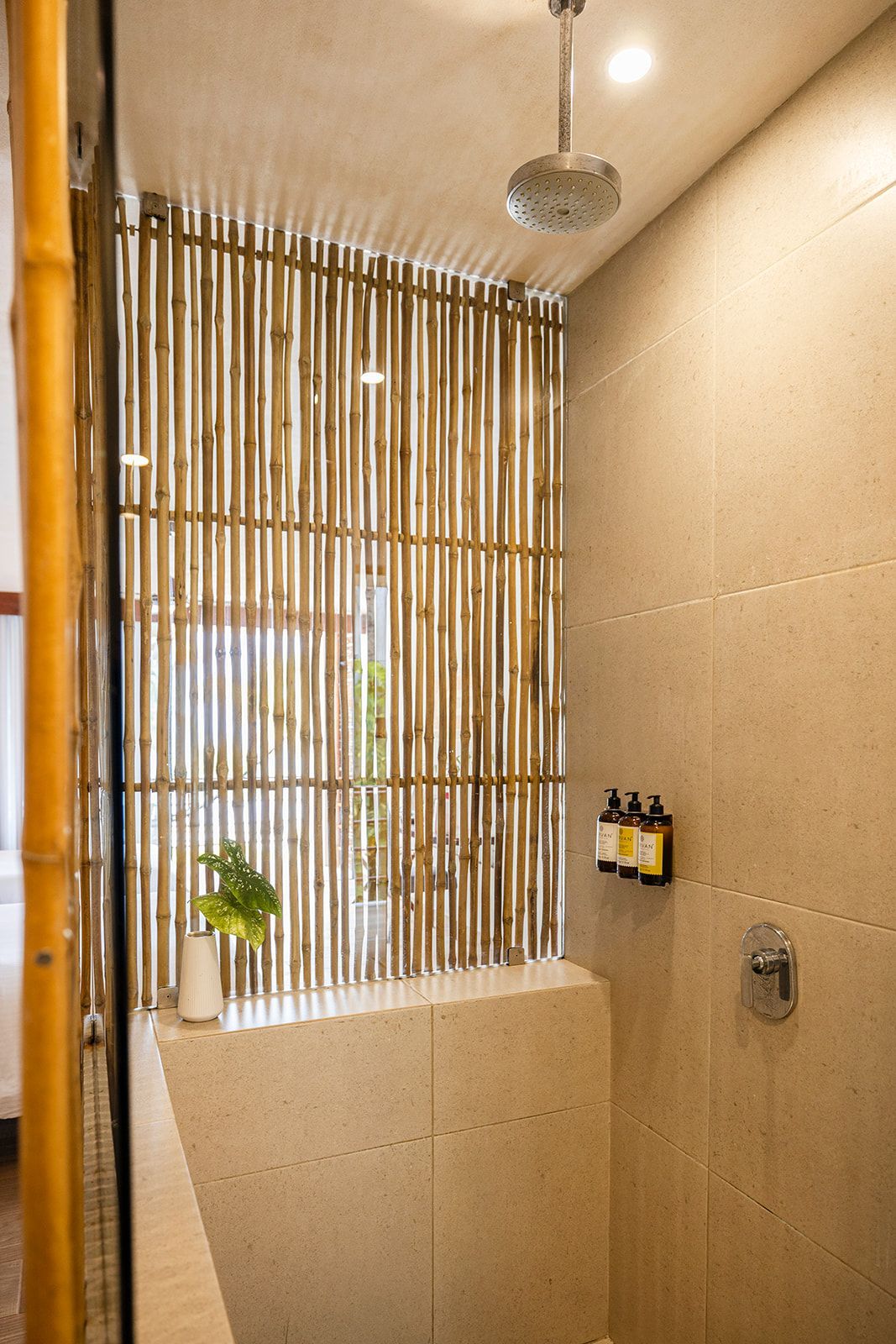 Shower stall with bamboo screen, overhead showerhead, and neutral-toned tiles.