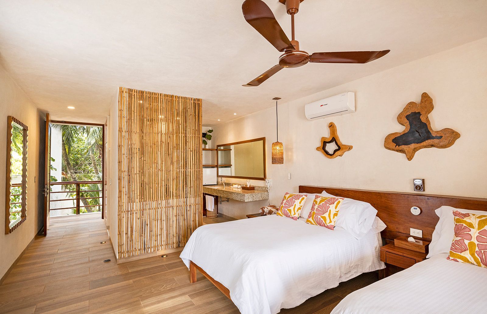 Bedroom with two beds, wooden headboards, and a bamboo screen separating the bathroom area.
