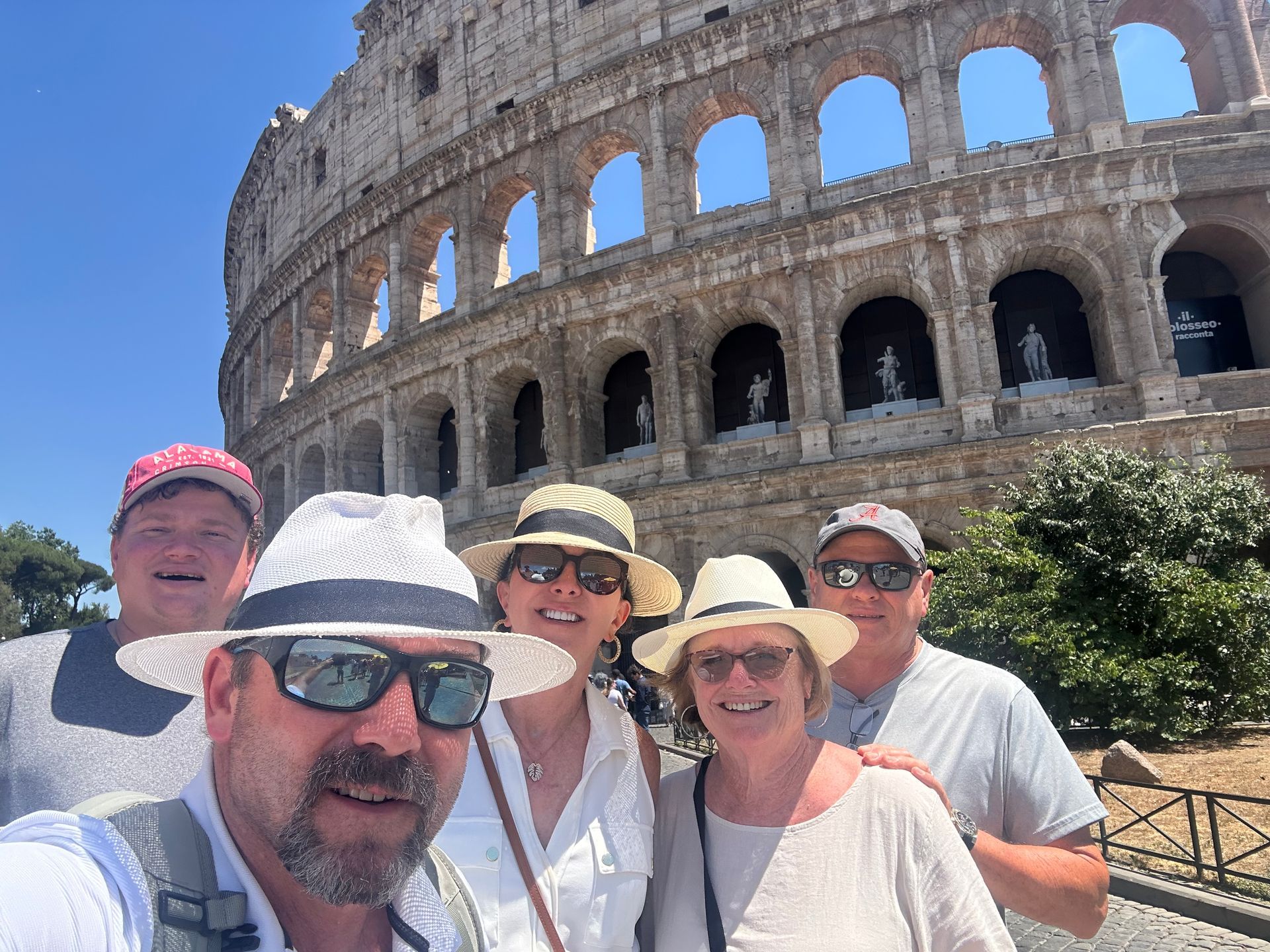 Group of people taking a selfie in front of the Colosseum in Rome, Italy on a sunny day.