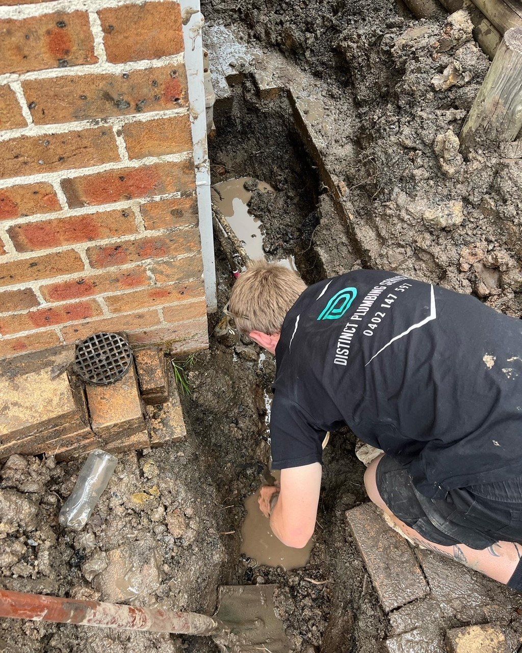Plumber Repairing Sink Siphon With Two Pipe Wrenches In Bathroom — Distinct Plumbing Services In Flinders NSW