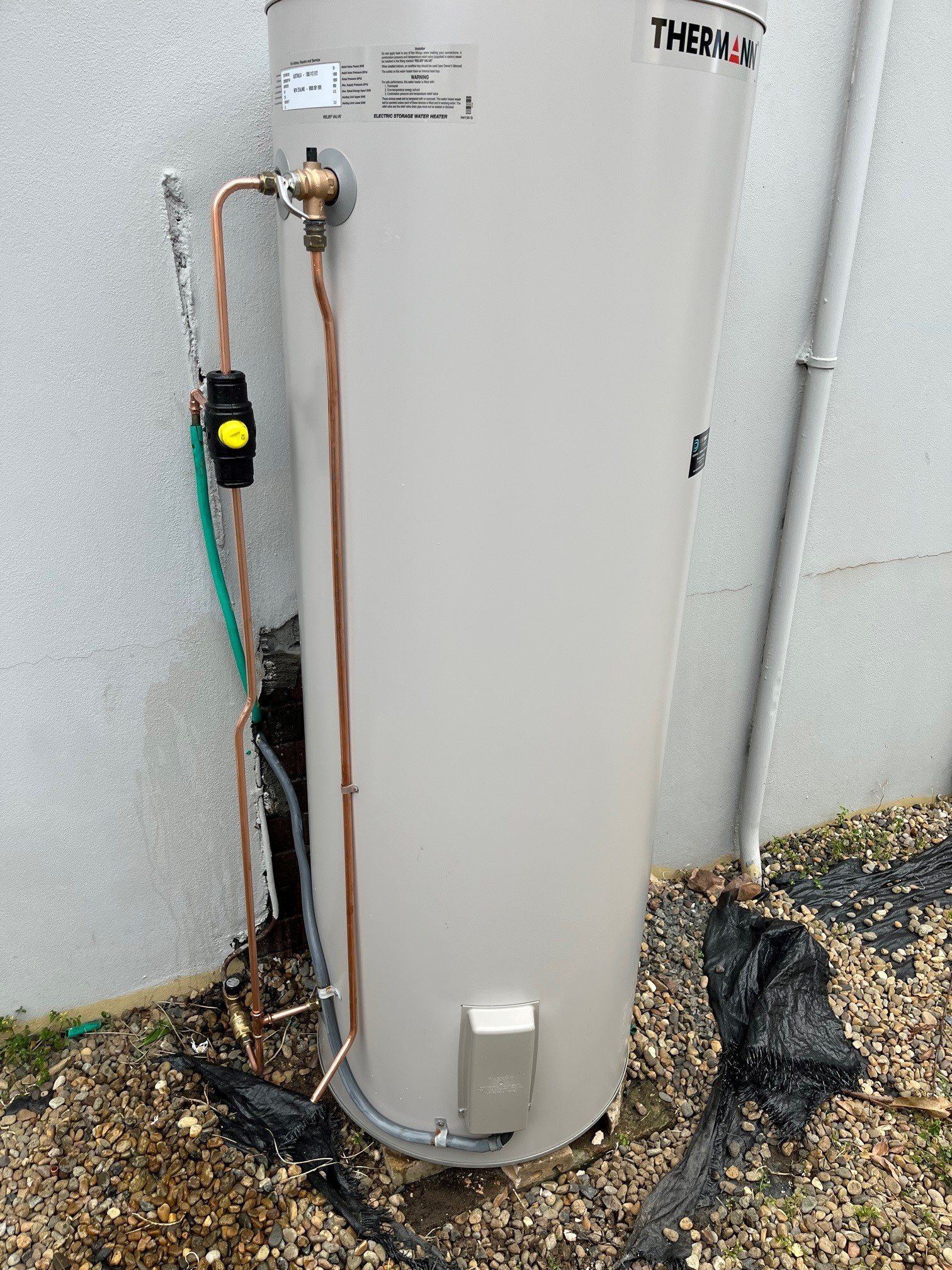 Man's Hands Unscrewing A Screw Nut On A Water Heater — Distinct Plumbing Services In Flinders NSW