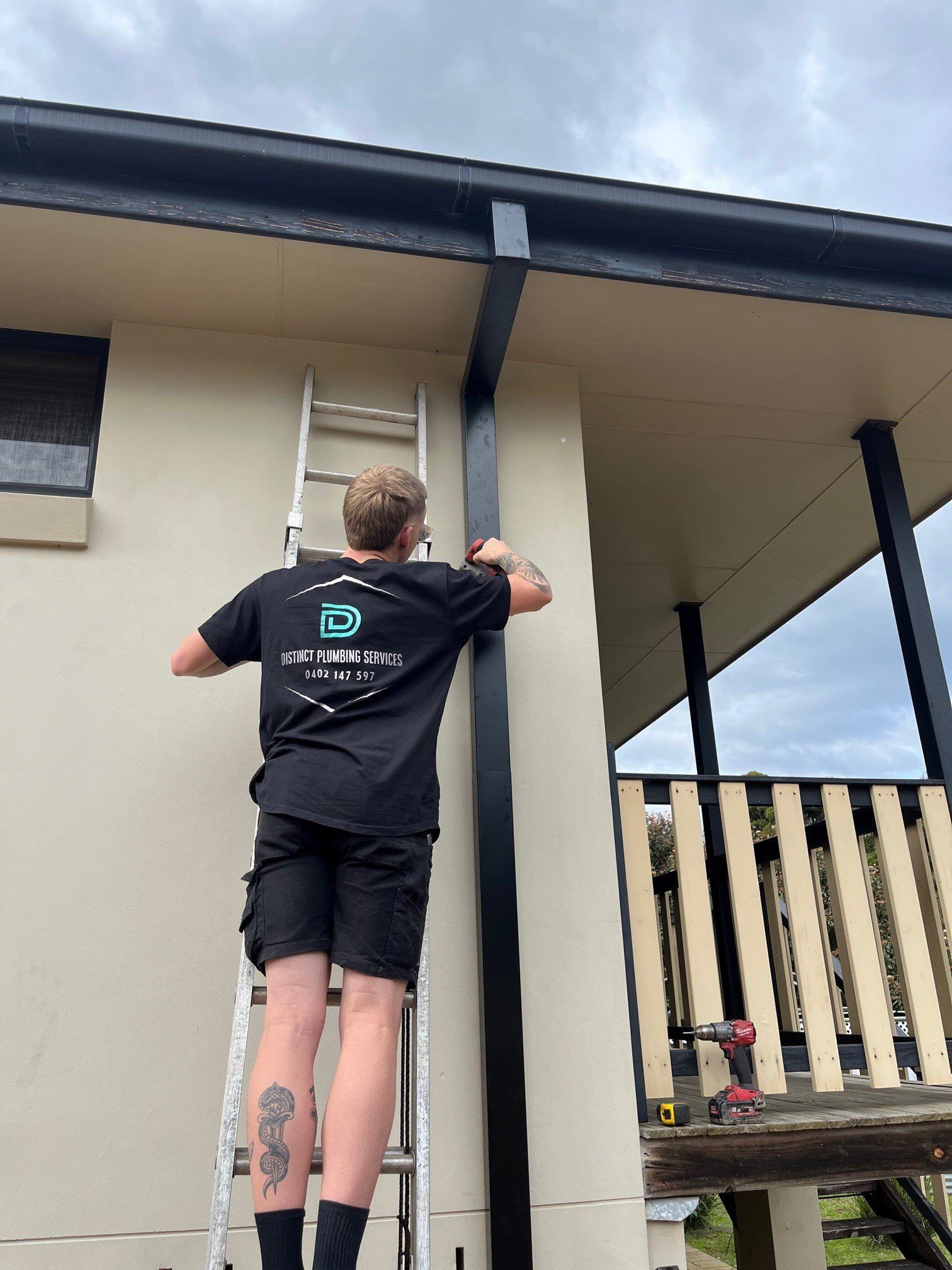 Young Plumber Working With Pipe Wrench And Tools In Kitchen — Distinct Plumbing Services In Kiama, NSW