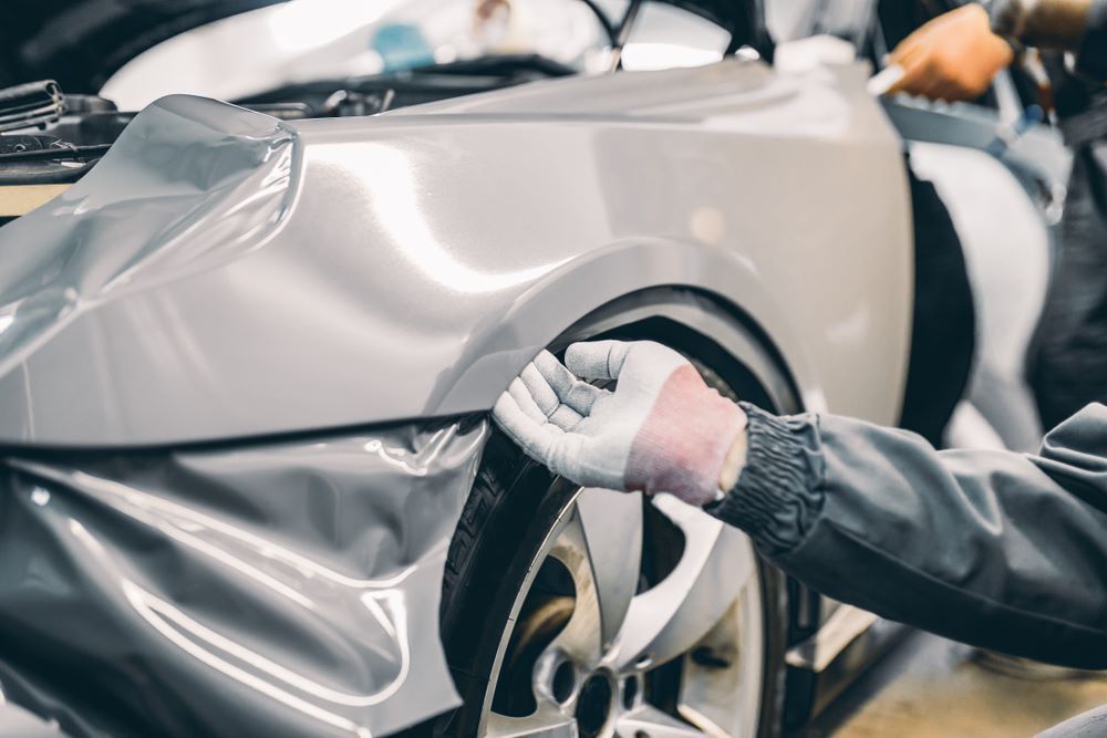 A Man is Wrapping a Car With Plastic Wrap — Camden Haven Panel Works In Laurieton, NSW