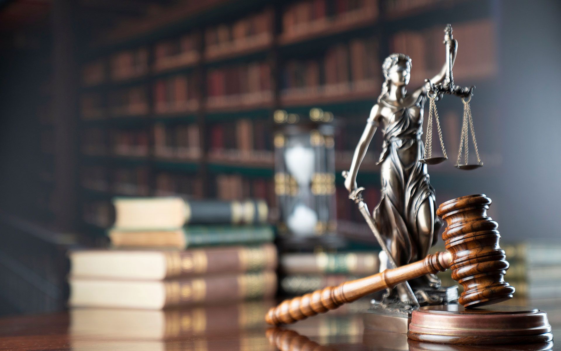 Statue of Lady Justice with scales and gavel on desk in library.