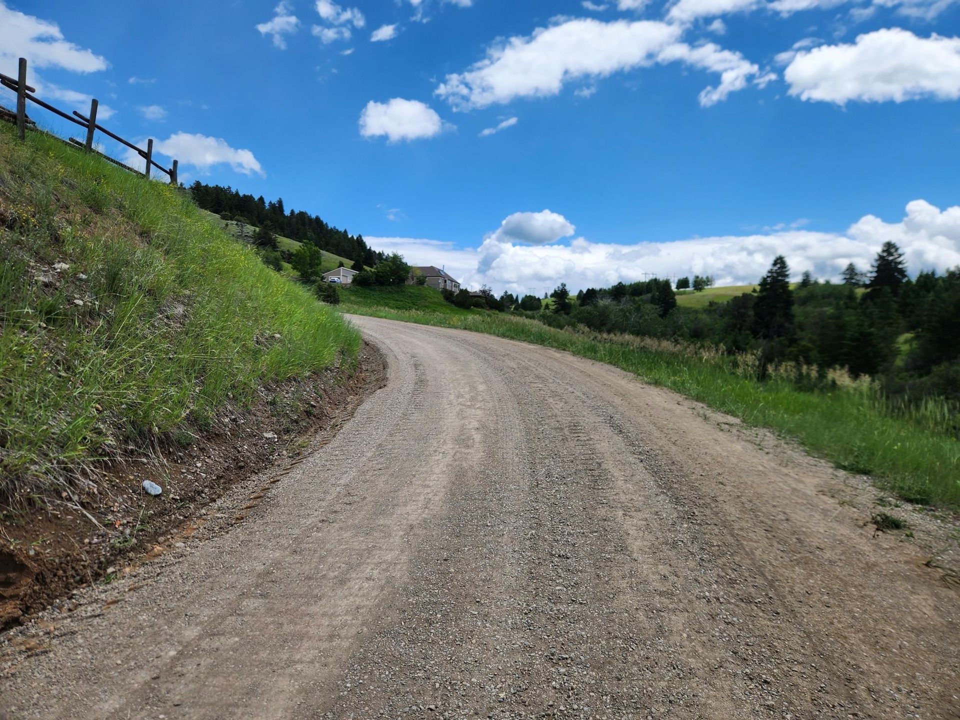 A dirt road with a wooden fence on the side of it