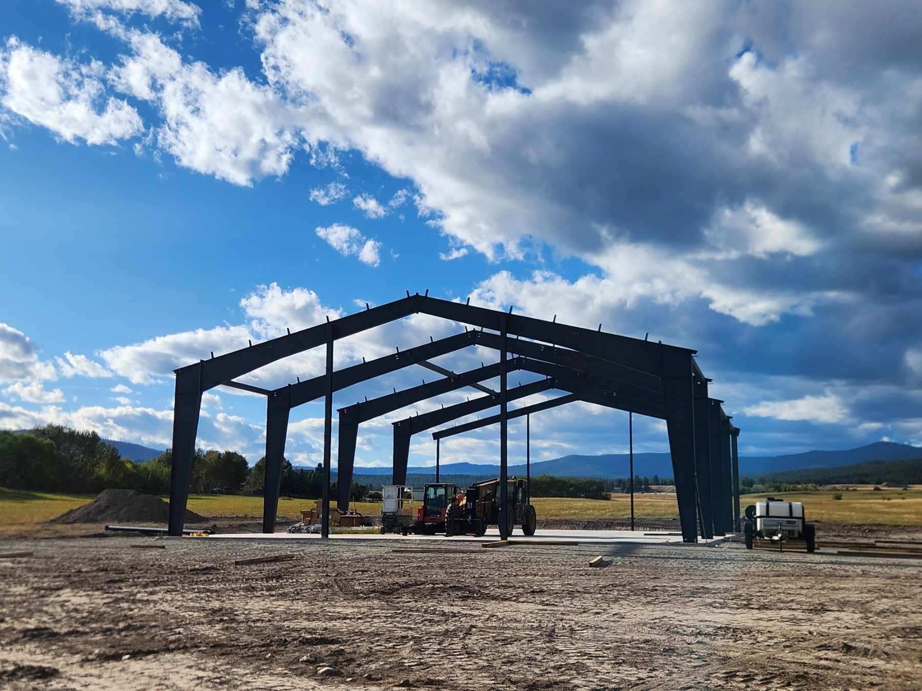 A large metal structure is being built in the middle of a dirt field.