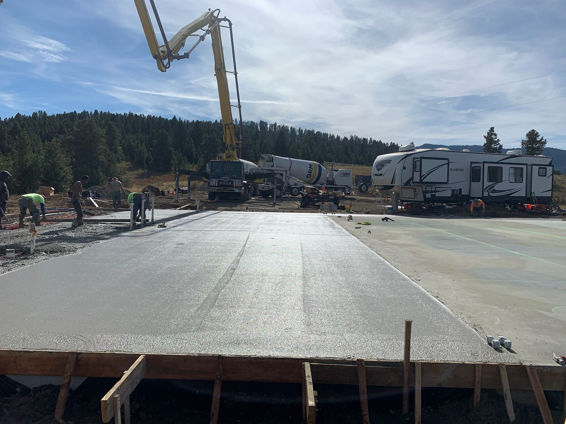 A concrete pump is being used to pour concrete into a parking lot.