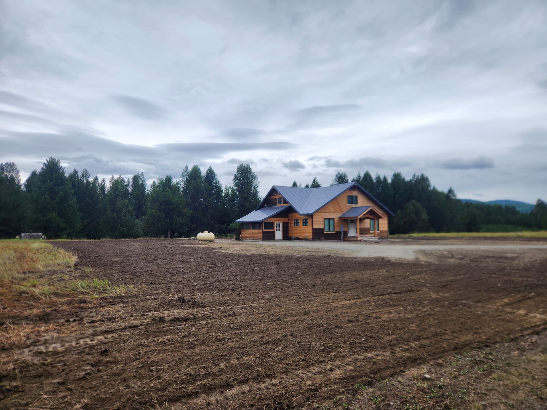Prepared construction site with graded dark soil leading to newly built mountain home