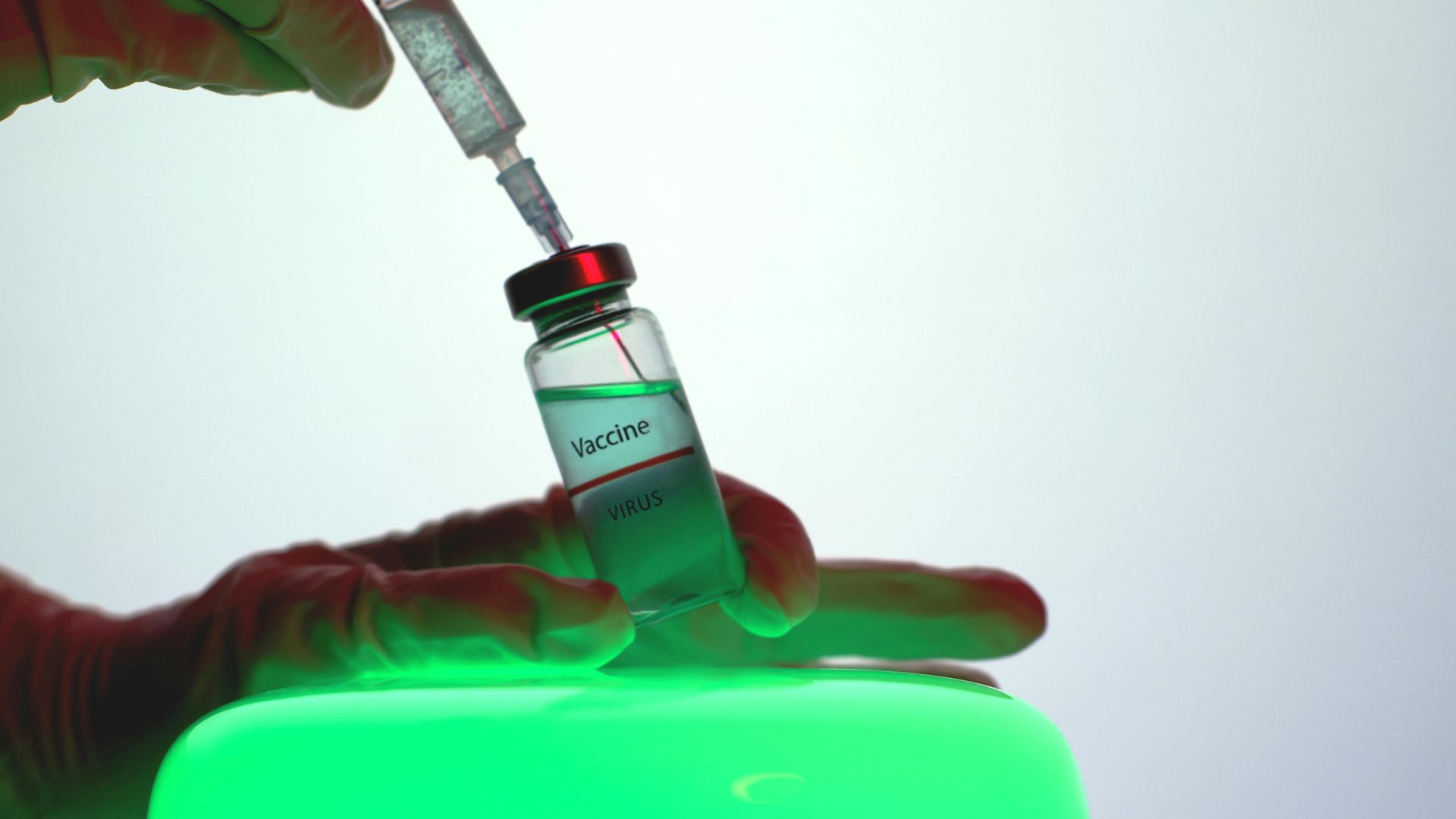 Gloved hand filling a syringe from a vial labeled