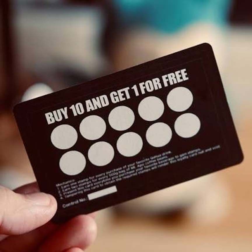 Hand holding a dark loyalty card reading “BUY 10 AND GET 1 FOR FREE” with ten white circles