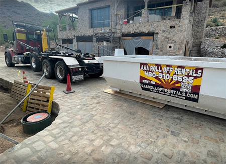 Tow truck parked beside a stone building, with cones and a rental sign on the barrier.