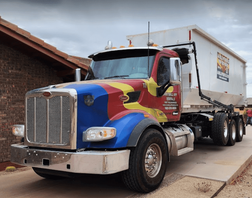 Blue-and-red semi truck parked beside a building, showing a white trailer and chrome grille.