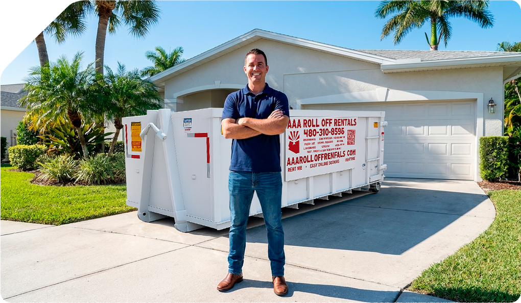 Man standing in front of a white dumpster trailer in a sunny suburban driveway, arms crossed.
