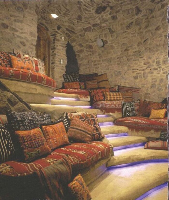 A room with a lot of pillows on the couch and stairs