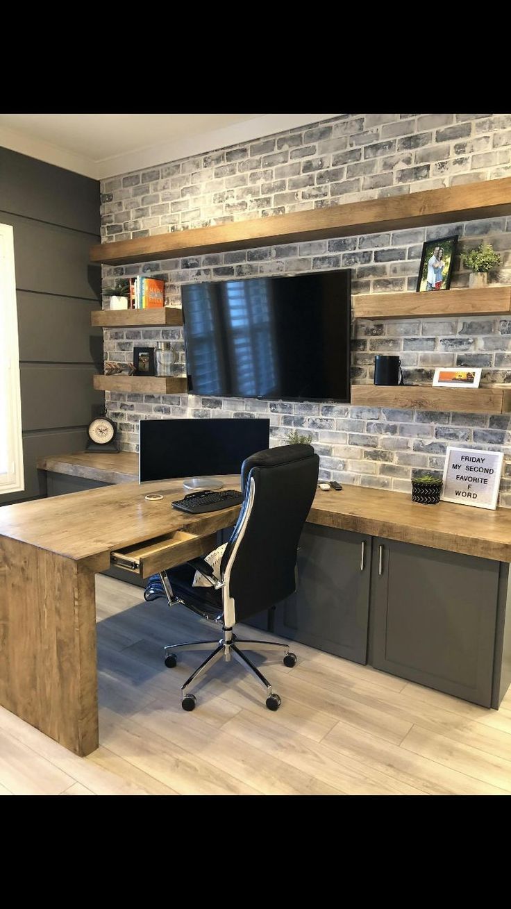 A home office with a desk , chair , computer and television.