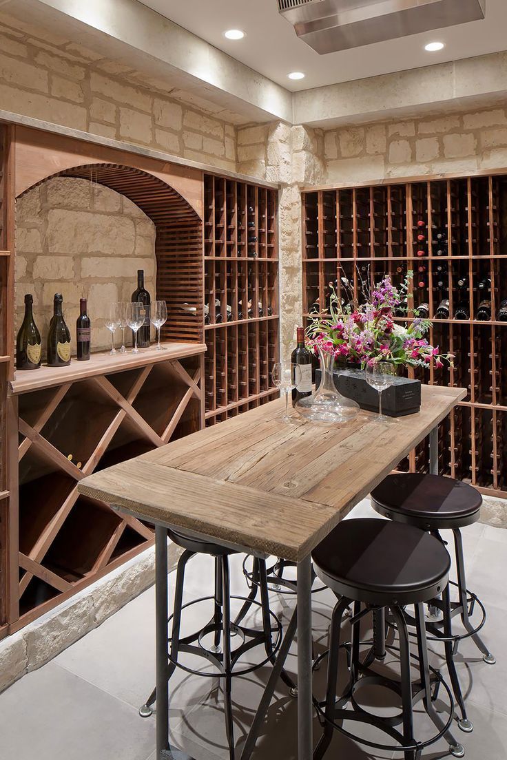 A wine cellar with a table and stools and bottles of wine.
