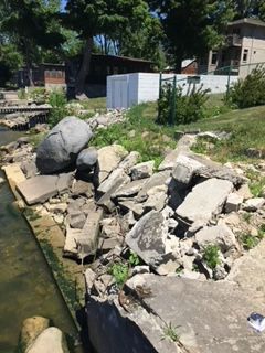 A pile of rocks is sitting next to a body of water.
