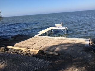 Concrete dock extending into calm blue water under a clear sky