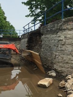 A bulldozer is helping retain a stone wall.
