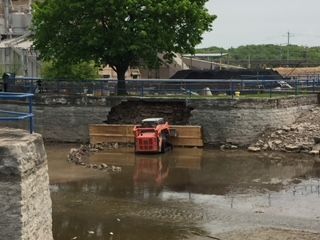 A red tractor is sitting in the middle of a river.
