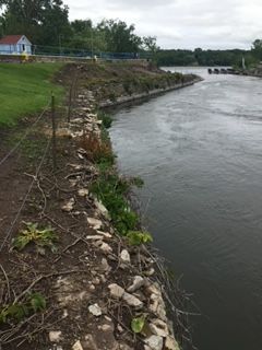 A river with a fence along the shore and a house in the background.