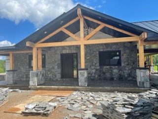 A house is being built with a stone facade and wooden beams.
