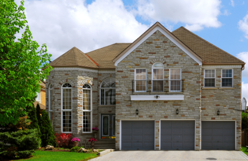A large brick house with three garage doors and a large driveway
