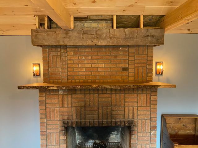 Brick fireplace with wooden mantel and sconces in a cozy room