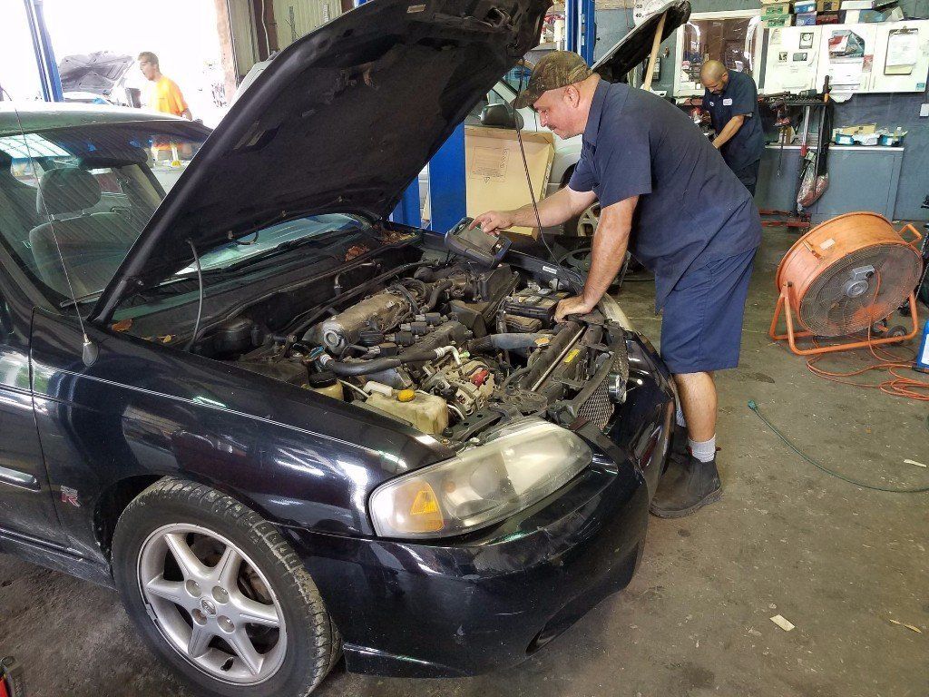 auto mechanic working on alternator under the hood