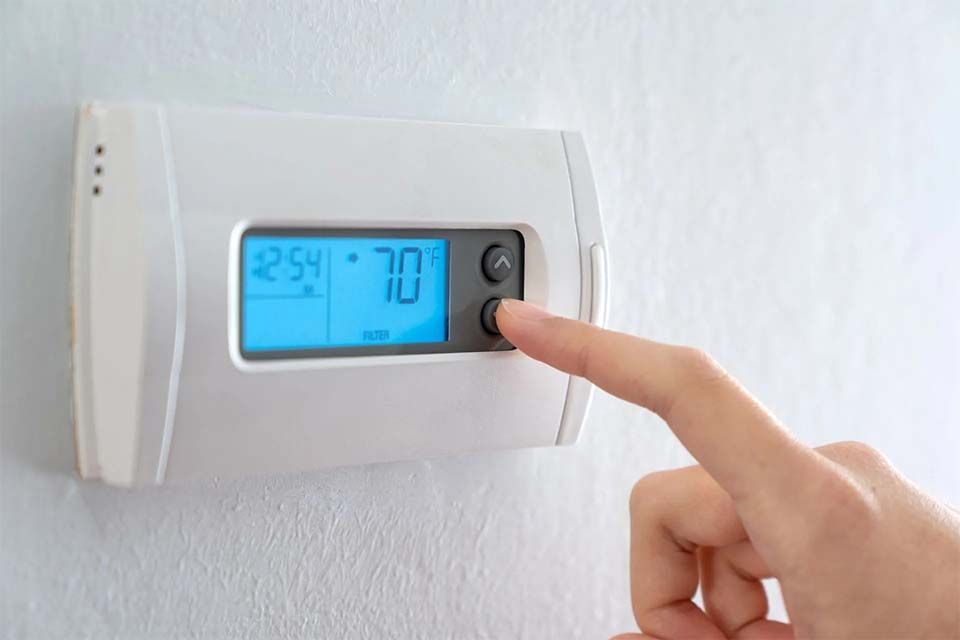 Someone setting a digital thermostat