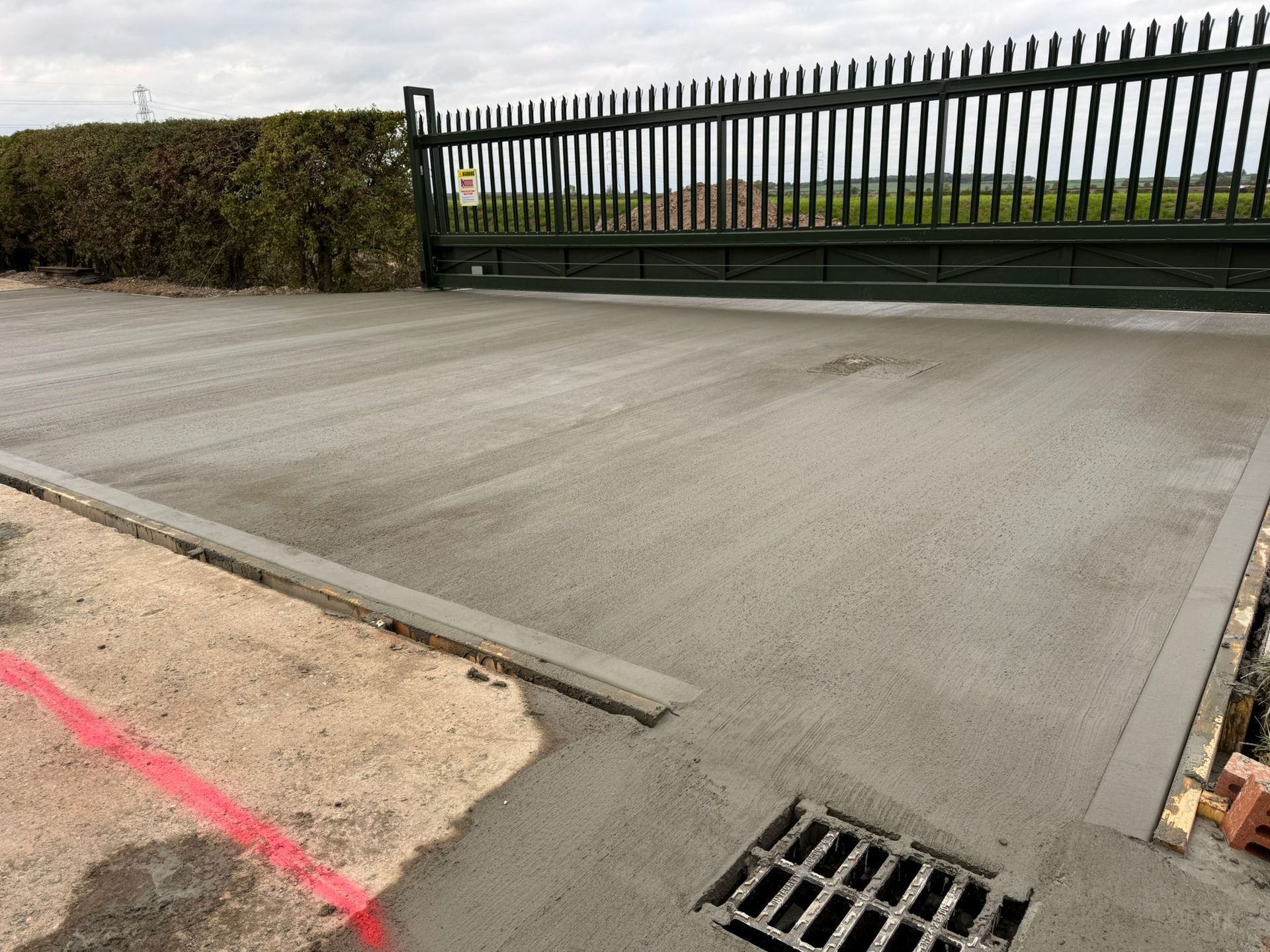 Concrete driveway with drainage grate and security gate.