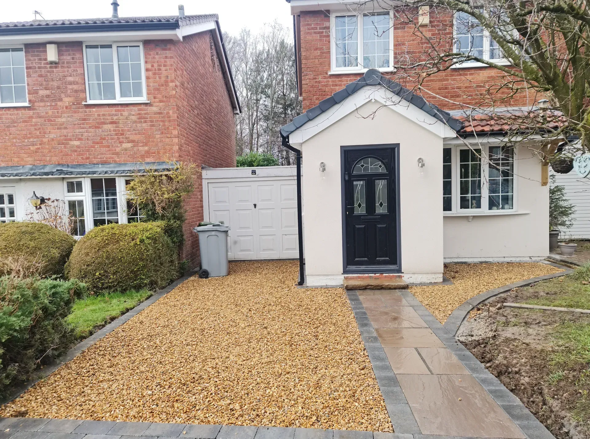 House with gravel driveway and path leading to a front porch and door.