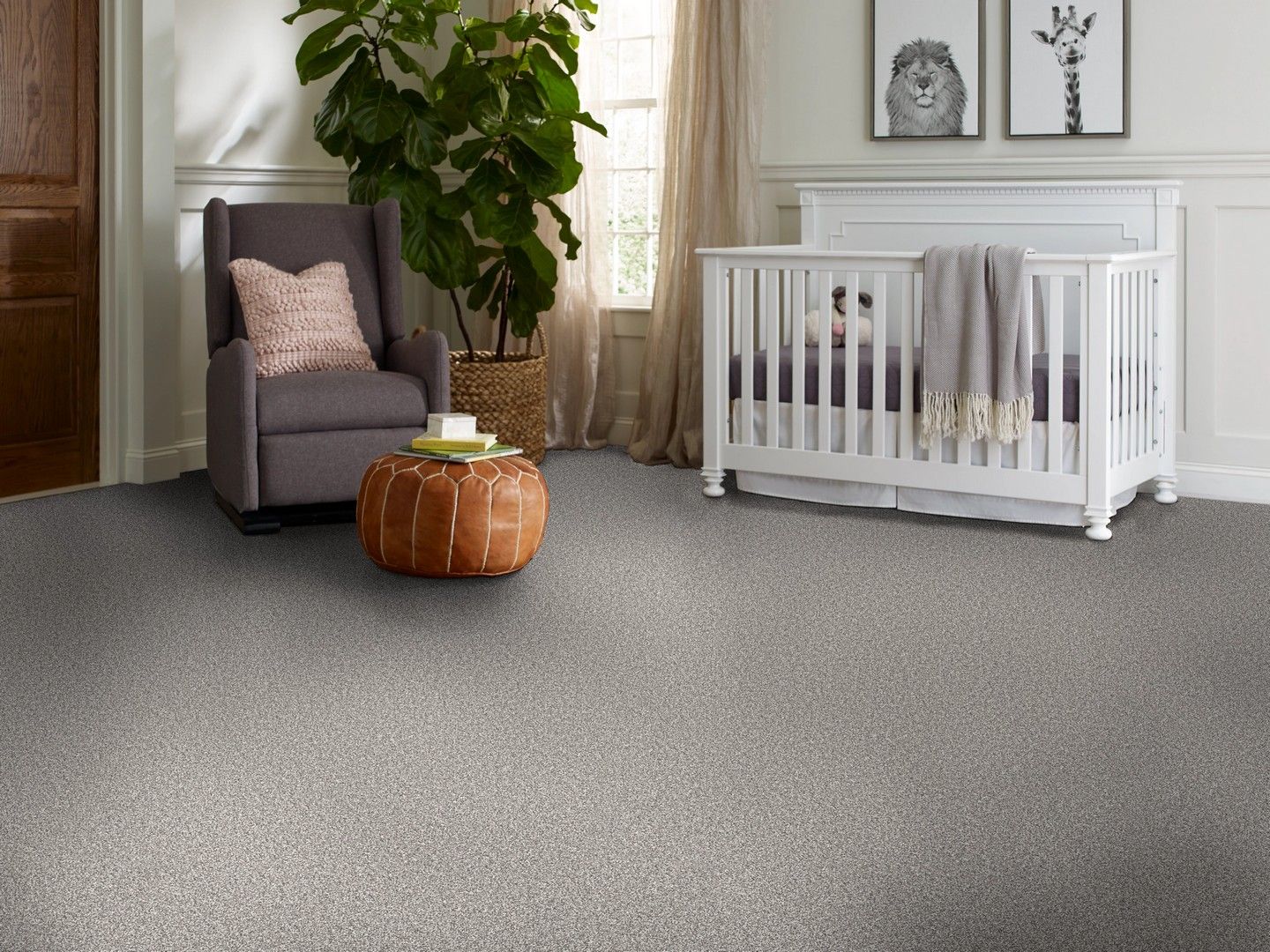 Gray-carpeted nursery with white crib, armchair, ottoman, and tall plant by the window