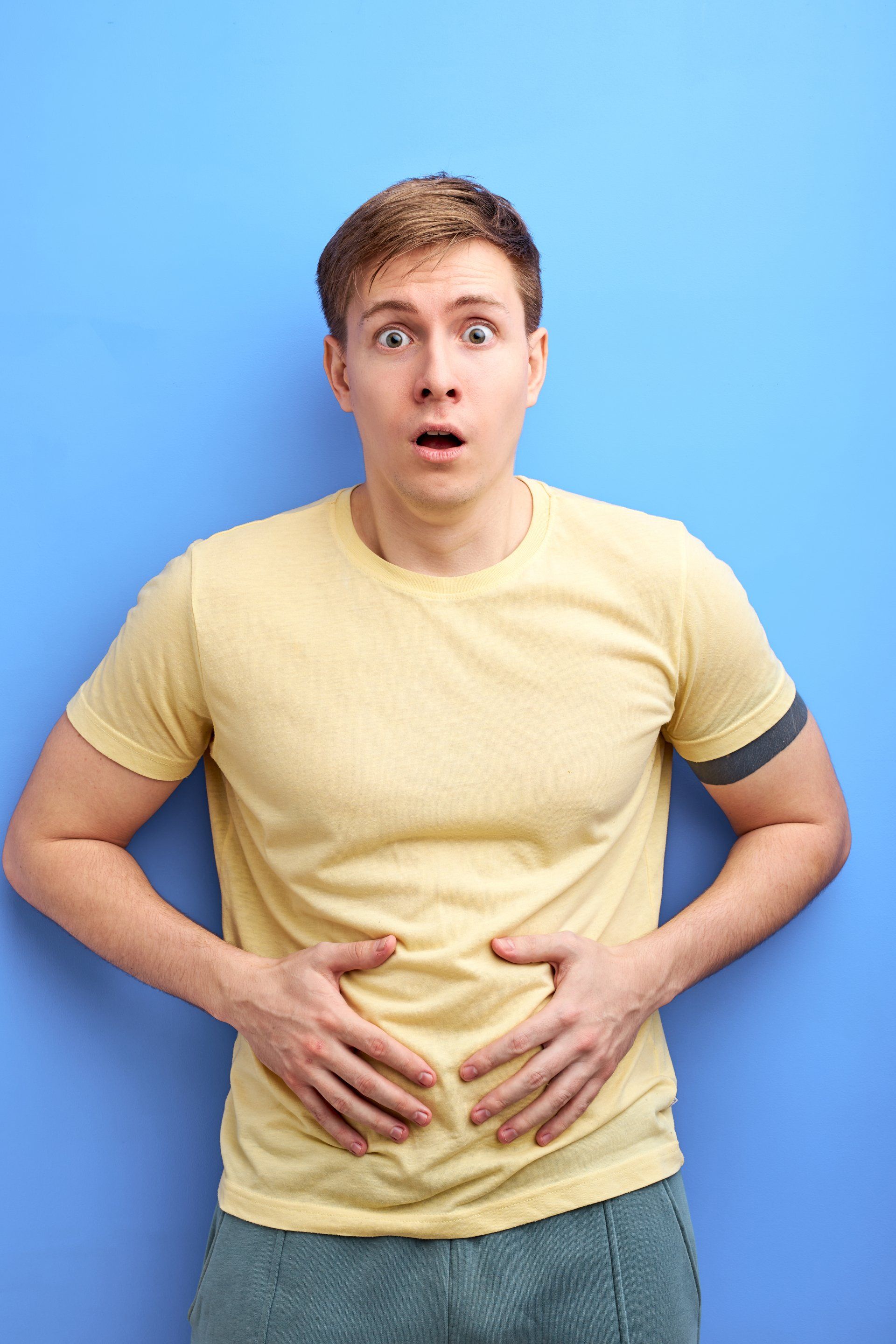 Man holding stomach with look on suprise on his face.