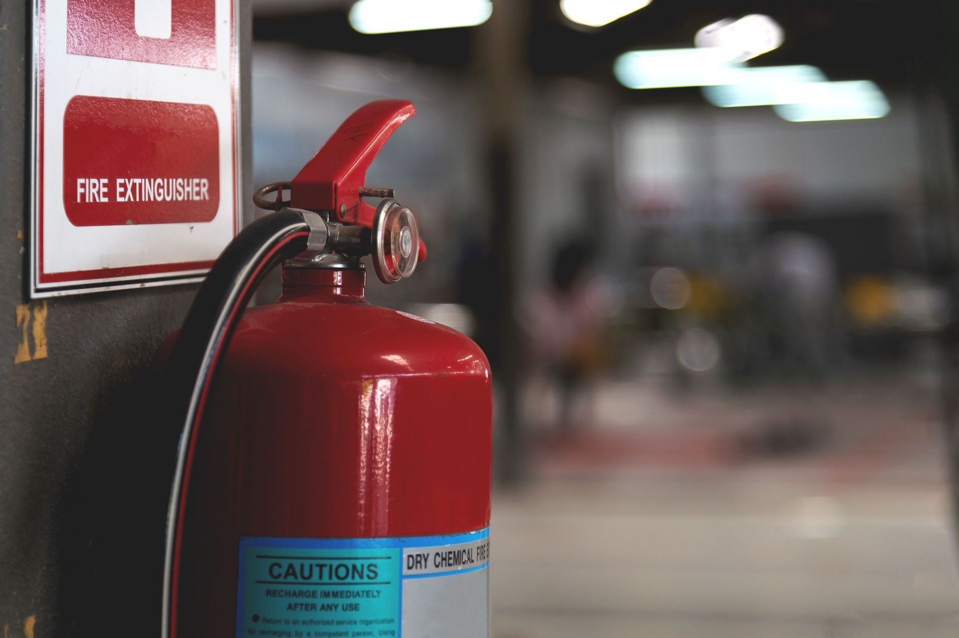 Red fire extinguisher mounted on a wall in an indoor hallway, with a fire equipment sign nearby Red fire extinguisher mounted on a wall in an indoor hallway, with a fire equipment sign nearby
