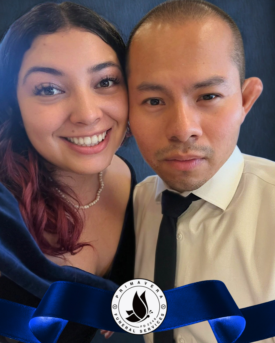 Smiling couple posing close together with a blue ribbon and circular emblem in the foreground.