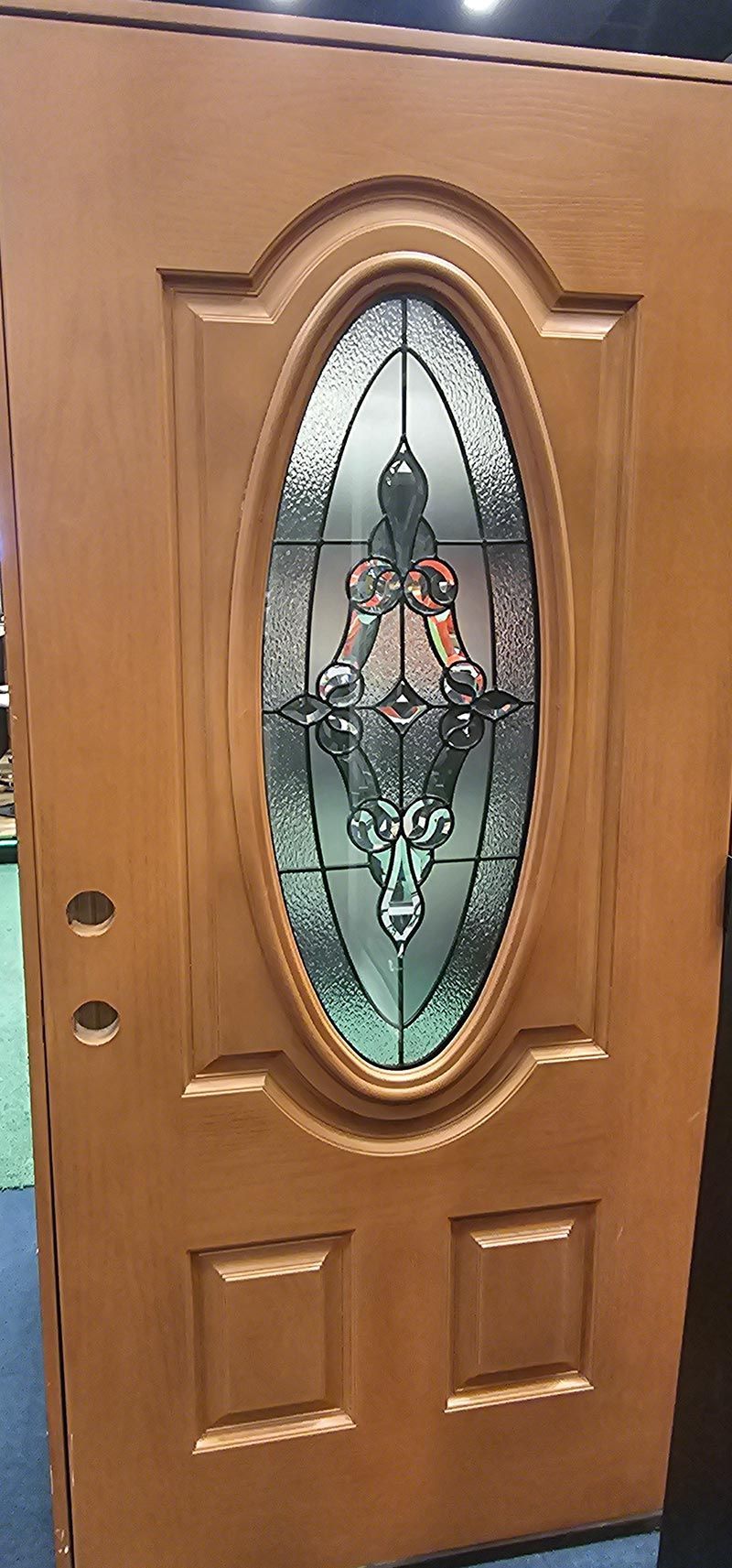 Wooden front door with an oval frosted glass insert and decorative metalwork.