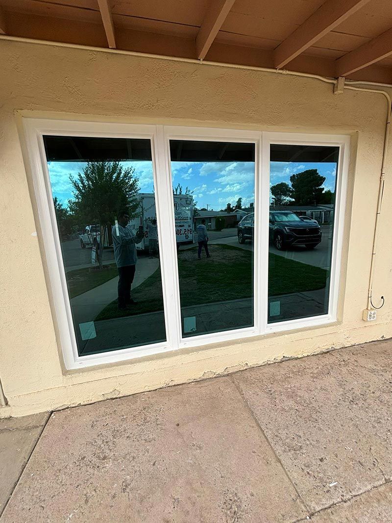 Three white-framed glass doors reflecting the outdoors under a covered patio.
