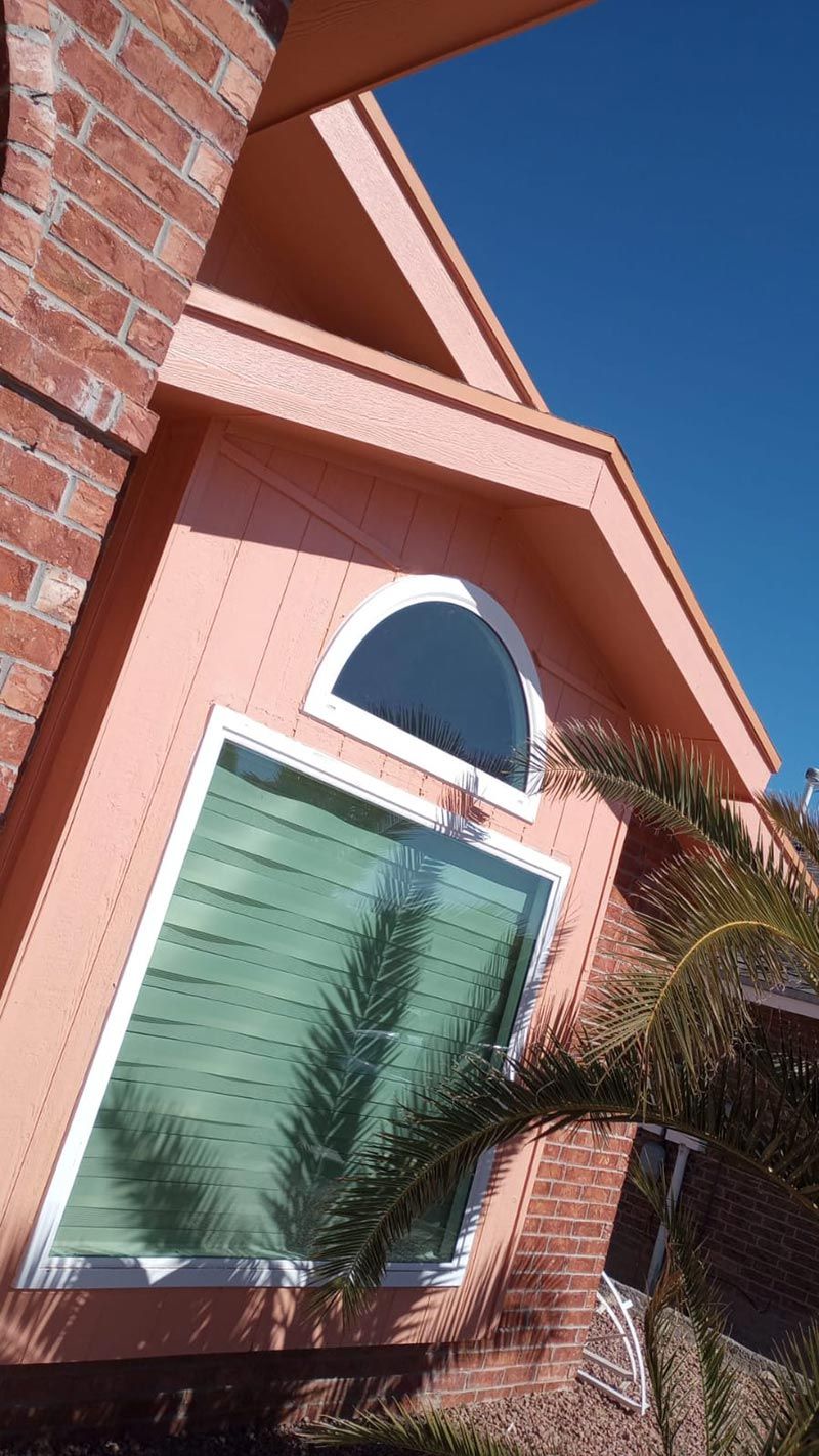 Brick house exterior with peach gable, white-framed window, and blue sky above