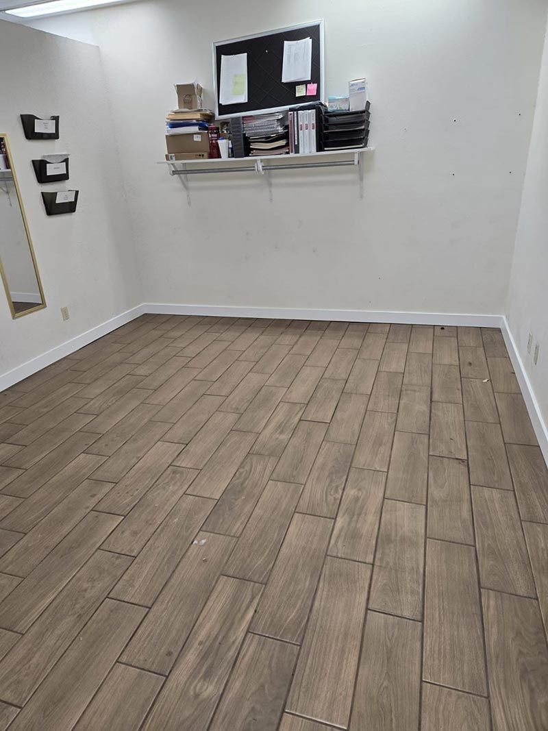 Empty room with wood-look flooring, white walls, and a small shelf on the back wall.