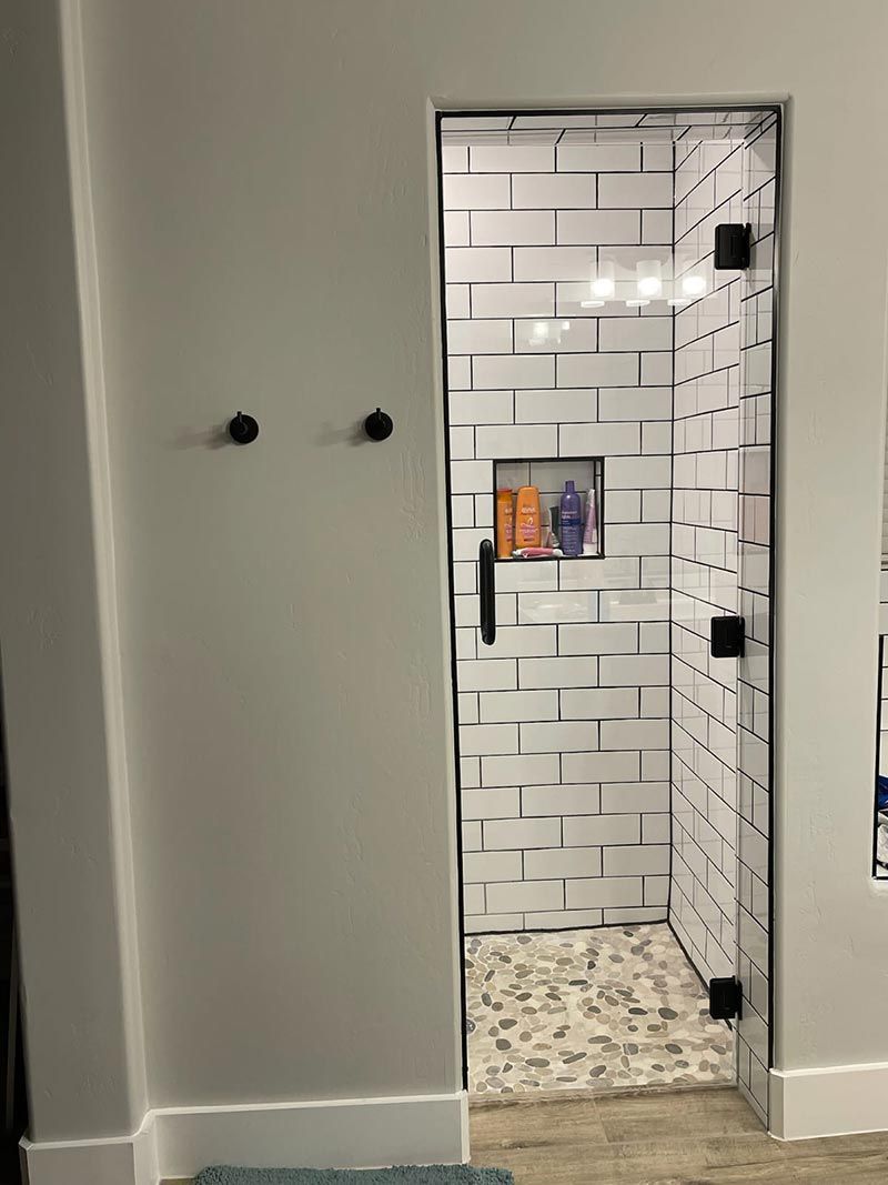 Open bathroom doorway with white subway tile, black fixtures, and a speckled tile floor