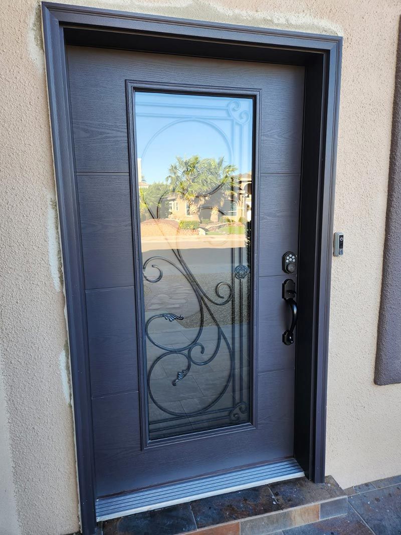 Front door with frosted glass panel and decorative metal scrollwork on a stucco house.
