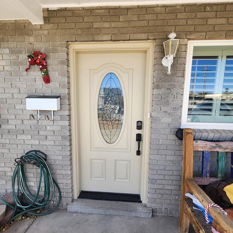 Front porch with a cream front door, brick wall, hose reel, mailbox, and window