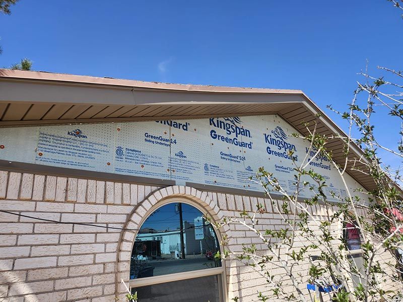 Stone building with arched window and blue-and-white sign under a clear sky